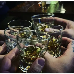 four glasses of whiskey being toasted