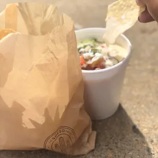 a hand holding a tortilla and a bag of chips