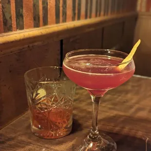a cocktail in a coupe glass with a lemon peel