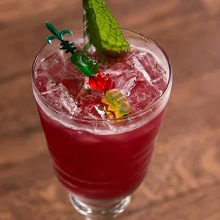 a glass of red drink with a green garnish