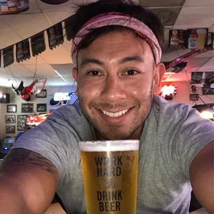 a man with a headband holding a pint of beer
