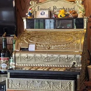 a gold cash register and bottles of liquor