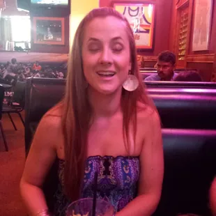 a woman sitting at a table with a drink