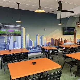 Covered patio with TV&apos;s and mural of the Houston skyline