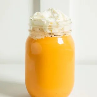 a jar of orange juice with whipped cream