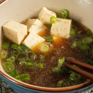 a bowl of soup with tofu and broccoli