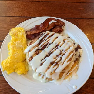 Cinnamon Swirl Sunrise - Cinnamon swirl pancakes topped with cream cheese glaze. Eggs and choice of bacon or sausage.