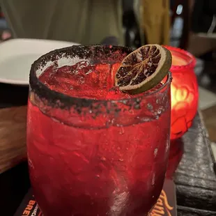 a red cocktail with a slice of lemon