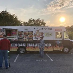 two men standing in front of a food truck