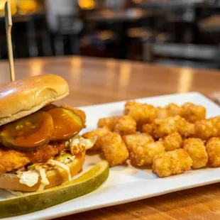 a plate with a sandwich and tater tots