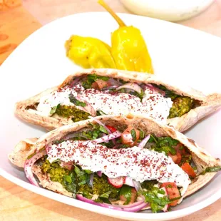 Homemade falafel patties stuffed in a freshly baked pita filled with coconut-tzatziki sauce, lemon-tahini, and a salad of Parsley, Mint, Red