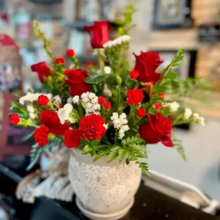 a white vase with red and white flowers