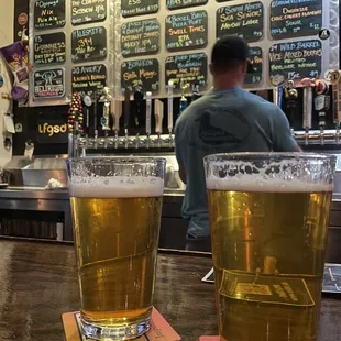 two glasses of beer on a bar