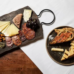 a plate of meat, cheese, bread, and olives