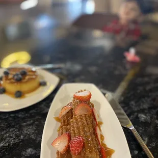 a plate of french toast with strawberries and syrup