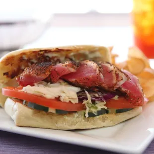 Seared Ahi Tuna Sandwich with cucumbers, tomatoes, Asian slaw and wasabi aioli on a ciabatta roll.