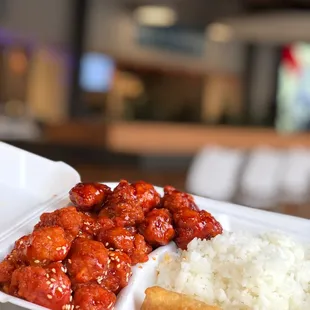 a hand holding a takeout container of food