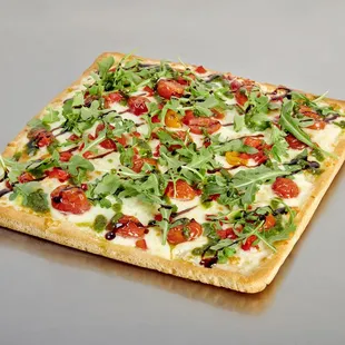 a flatbread pizza topped with tomatoes and arugula