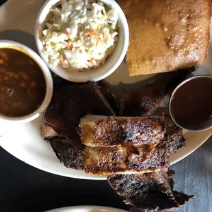a plate of ribs, coleslaw, and sides