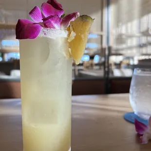 a glass of lemonade with a flower garnish
