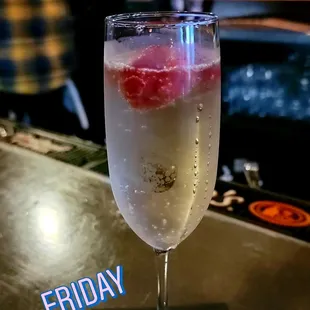 a glass of wine with a raspberry in it