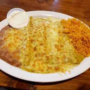 Green cheese enchiladas, rice and beans with a side of sour cream.