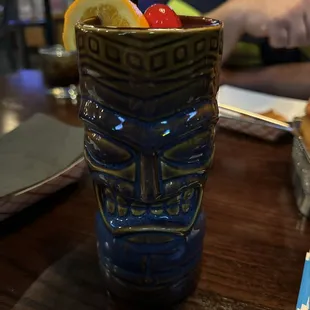 a tiki mug with a straw and a slice of orange