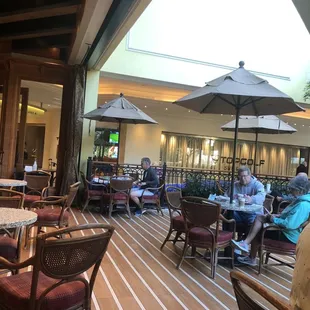 people sitting at tables with umbrellas