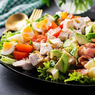 a salad with chicken, lettuce, tomatoes, and hard boiled eggs