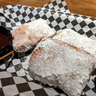 two powdered sugar pastries and a dipping sauce