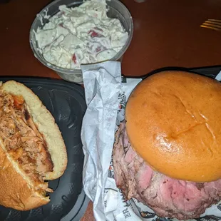 Half of a pulled chicken sandwich, a med rare pit beef and potato salad, to go
