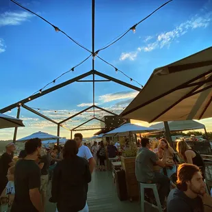 people sitting and standing under umbrellas