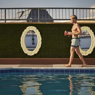 a man walking by a swimming pool