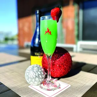 a green cocktail with a strawberries garnish