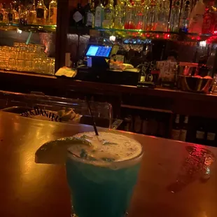 a blue cocktail with a lime garnish