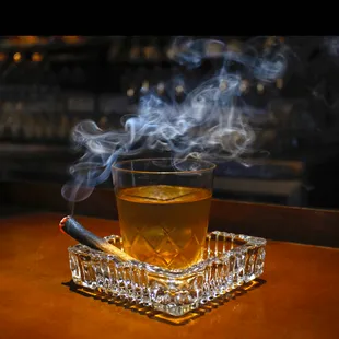 CIGAR BOX mezcal, smoked black tea syrup, scrappy's lavender bitters, tobacco essence, served on an ashtray with a flamed cinnamon stick