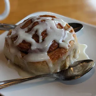 a cinnamon roll with icing and a spoon