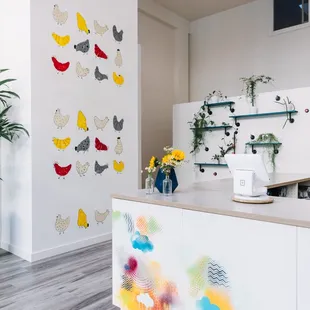 a kitchen with a white counter and colorful artwork on the wall