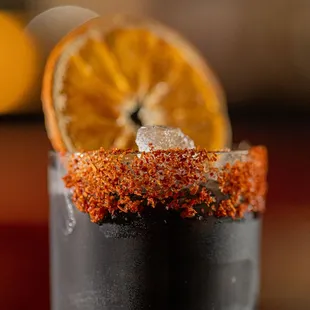 a close up of a drink with a slice of orange on the rim