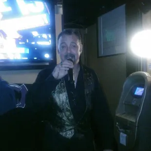 a man holding a microphone in front of a tv