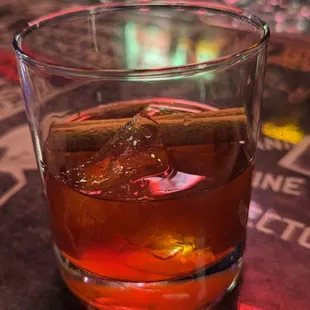 a glass of whiskey with a cinnamon stick