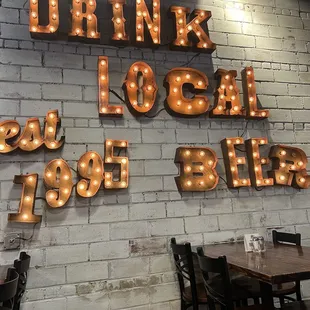 a brick wall with a sign that says drink local beer