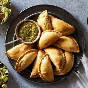 a plate of empanadas and a bowl of salad