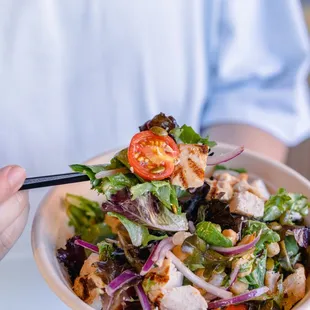 a person holding a bowl of salad