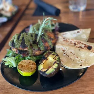 Half chicken grilled with Chimichurri sauce, with grilled avocado, tortillas and lime