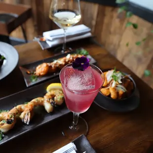 a wooden table with plates of food and a glass of wine