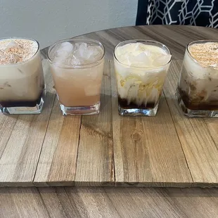 four different drinks on a wooden tray