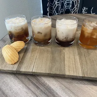 four different drinks on a wooden tray