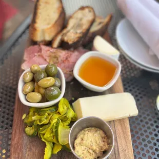 a platter of meat, cheese, olives, and bread