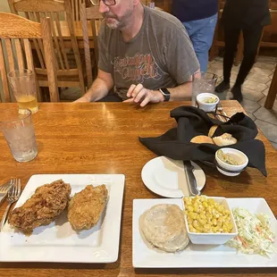 a man sitting at a table with two plates of food